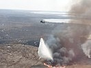 Zwei S-70 "Black Hawk"-Hubschrauber im Kampf gegen einen Schilfbrand.