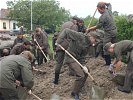 Bundesheer-Soldaten befüllen Sandsäcke für Dämme, rechts Ski-Ass C. Raich.