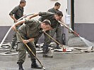 Die Soldaten reinigen die überschwemmten Straßen.