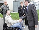 Verteidigungsminister Darabos begrüßt Rollstuhl-Basketballer Nori Selimi.