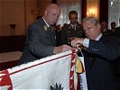 General Ertl und Staatssekretär Winkler befestigen die neuen Fahnenbänder...