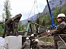 Ein Schwerlastkran hebt die Brücke auf die Widerlager.