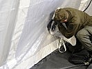 Ein Gebläseschlauch wird im Inneraum des "COLPRO"-Zeltes angebracht. (Bild öffnet sich in einem neuen Fenster)