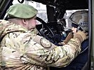 Ein Soldat hilft einem jungen Besucher beim Aufsetzen des Kampfhelmes. (Bild öffnet sich in einem neuen Fenster)