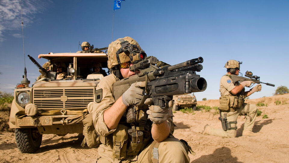 Soldaten mit Gewähr und Fahrzeug im Einsatz