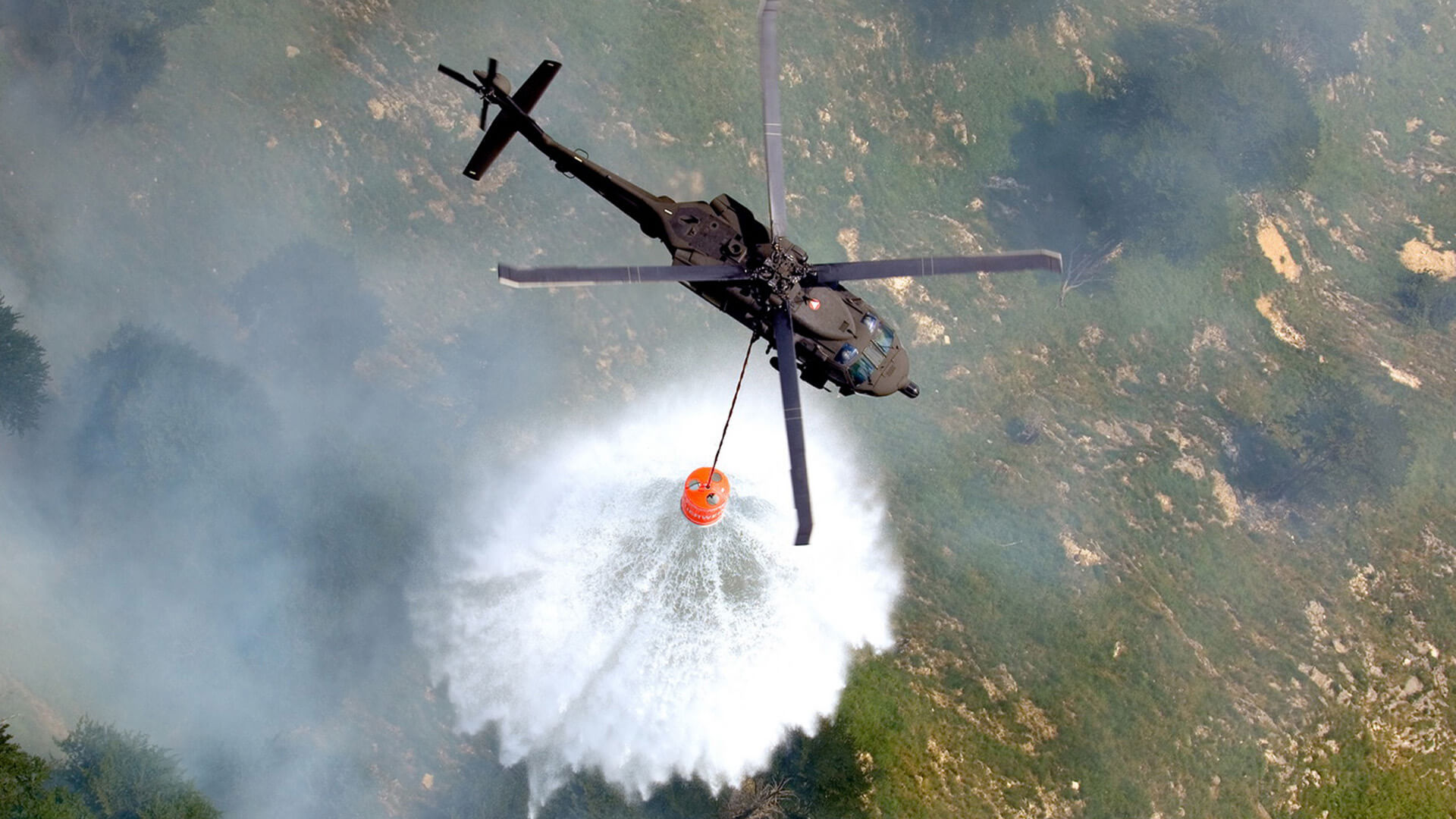 Hubschauber des Österreichischen Bundesheeress löscht Waldbrand mit Wasser