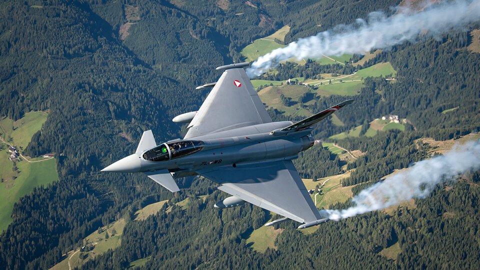 Kampfflugzeug Eurofighter EF 2000 des Österreichischen Bundesheereses fliegt über Wald